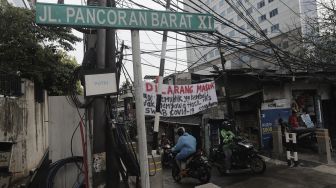 Pengendara melintas di dekat spanduk peringatan untuk pemudik di Jalan Pancoran Barat XI, Jakarta, Senin (17/5/2021). [Suara.com/Angga Budhiyanto]