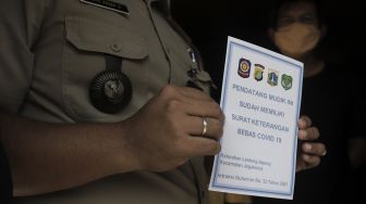 Lurah Lenteng Agung, Bayu Pasca menunjukkan stiker tanda memiliki surat keterangan bebas COVID-19 sebelum memasangkannya pada rumah pemudik yang baru kembali ke Jakarta di kawasan Lenteng Agung, Jakarta, Senin (17/5/2021). [Suara.com/Angga Budhiyanto]