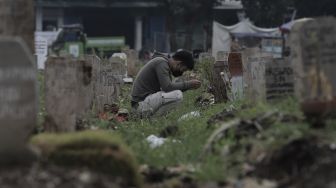 Warga berdoa di makam keluarganya saat melakukan ziarah kubur di pemakaman khusus COVID-19 di TPU Srengseng Sawah, Jakarta, Selasa (18/5/2021). [Suara.com/Angga Budhiyanto]