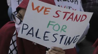 Seorang massa aksi membawa poster saat mengikuti aksi solidaritas dukung Palestina terkait kekerasan yang terjadi beberapa waktu lalu oleh Israel di depan Kedubes AS, Jakarta, Selasa (18/5/2021). [Suara.com/Angga Budhiyanto]
