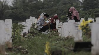 Warga berdoa di makam keluarganya saat melakukan ziarah kubur di pemakaman khusus COVID-19 di TPU Srengseng Sawah, Jakarta, Selasa (18/5/2021). [Suara.com/Angga Budhiyanto]