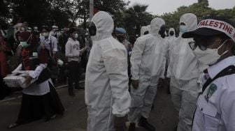 Polisi memakai baju hazmat memberi imbauan kepada massa yang mengikuti aksi solidaritas dukung Palestina di depan Kedubes AS, Jakarta, Selasa (18/5/2021). [Suara.com/Angga Budhiyanto]