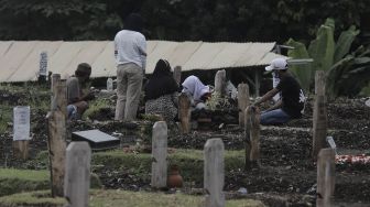 Warga berdoa di makam keluarganya saat melakukan ziarah kubur di pemakaman khusus COVID-19 di TPU Srengseng Sawah, Jakarta, Selasa (18/5/2021). [Suara.com/Angga Budhiyanto]