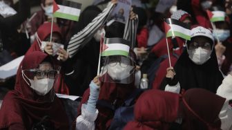 Massa aksi membawa miniatur bendera Palestina saat mengikuti aksi solidaritas dukung Palestina terkait kekerasan yang terjadi beberapa waktu lalu oleh Israel di depan Kedubes AS, Jakarta, Selasa (18/5/2021). [Suara.com/Angga Budhiyanto]
