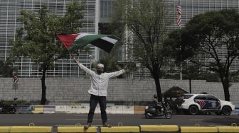Seorang massa aksi mengibarkan bendera Palestina saat mengikuti aksi solidaritas dukung Palestina terkait kekerasan yang terjadi beberapa waktu lalu oleh Israel di depan Kedubes AS, Jakarta, Selasa (18/5/2021). [Suara.com/Angga Budhiyanto]