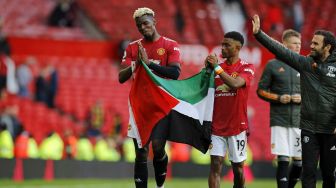 Pemain Manchester United Paul Pogba dan Amad Diallo mengibarkan bendera Palestina usai laga kontra Fulham yang berakhir imbang dalam lanjutan Liga Inggris di Old Trafford, Manchester, Inggris, Selasa (18/5/2021).  Laurence Griffiths / POOL / AFP
