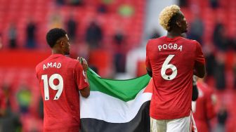 Pemain Manchester United Paul Pogba dan Amad Diallo mengibarkan bendera Palestina usai laga kontra Fulham yang berakhir imbang dalam lanjutan Liga Inggris di Old Trafford, Manchester, Inggris, Selasa (18/5/2021).  Laurence Griffiths / POOL / AFP
