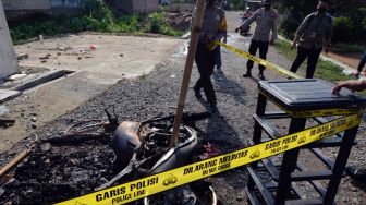 
Petugas memasang garis polisi di puing kendaraan dinas yang di bakar oleh massa di Mapolsek Candipuro, Lampung Selatan, Lampung, Rabu (19/5/2021). ANTARA FOTO/Ardiansyah