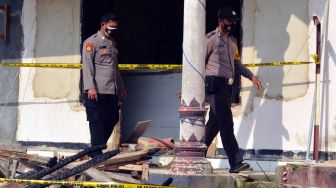 Petugas melintas di gedung Mapolsek Candipuro yang di bakar oleh massa di Desa Titi Wangi, Candipuro, Lampung Selatan, Lampung, Rabu (19/5/2021). ANTARA FOTO/Ardiansyah
