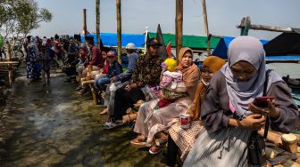 Sejumlah peziarah beristirahat seusai mengunjungi makam Simbah Kiai Abdullah Mudzakkir yang dijuluki 'Makam Terapung' di pesisir Desa Bedono, Sayung, Demak, Jawa Tengah, Kamis (20/5/2021). [ANTARA FOTO/Aji Styawan]