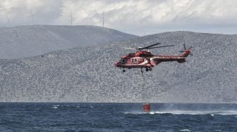 Helikopter pemadam kebakaran mengambil air untuk memadamkan api setelah terjadi kebakaran di bagian utara Korintus, pada (20/5/2021). [Louisa GOULIAMAKI / AFP]