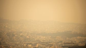 Kota Athena digambarkan melalui asap saat api berkobar di wilayah Korintus, pada (20/5/2021). [ANGELOS TZORTZINIS / AFP]