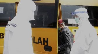 Seorang pemudik yang dikonfirmasi reaktif COVID-19 menaiki bus khusus pasien COVID-19 di Terminal Kampung Rambutan, Jakarta, Jumat (21/5/2021). [Suara.com/Dian Latifah]