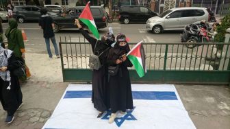 Massa pendukung Palestina saat menginjak bendera replika Israel di halaman Masjid Al Jihad, Jalan Abdullah Lubis, Medan. [Suara.com/Suhardiman]
