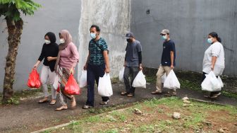 Warga mendistribusikan makanan dan bahan pokok untuk diberikan kepada warga yang menjalani isolasi mandiri dan terdampak Covid-19 di RT 03/ RW 03, Cilangkap, Jakarta Timur, Minggu (23/5/2021). [Suara.com/Alfian Winanto]