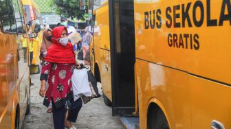 Warga RT 03 RW 03 menaiki mobil jemputan untuk selanjutnya dibawa ke RSDC Wisma Atlet di Cilangkap, Jakarta Timur, Minggu (23/5/2021). [Suara.com/Alfian Winanto]