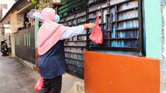 Warga mendistribusikan makanan dan bahan pokok untuk diberikan kepada warga yang menjalani isolasi mandiri dan terdampak Covid-19 di RT 03/ RW 03, Cilangkap, Jakarta Timur, Minggu (23/5/2021). [Suara.com/Alfian Winanto]