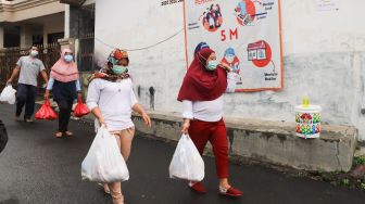 Warga mendistribusikan makanan dan bahan pokok untuk diberikan kepada warga yang menjalani isolasi mandiri dan terdampak Covid-19 di RT 03/ RW 03, Cilangkap, Jakarta Timur, Minggu (23/5/2021). [Suara.com/Alfian Winanto]