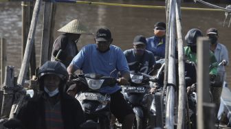 Sejumlah pengendara sepeda motor turun dari perahu eretan usai menyeberangi Kali Cagak, Jakarta Utara, Selasa (25/5/2021). [Suara.com/Angga Budhiyanto]