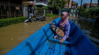 Seorang lansia menaiki perahu saat banjir melanda Kampung Bojongasih, Dayeuhkolot, Kabupaten Bandung, Jawa Barat, Selasa (25/5/2021). ANTARA FOTO/Raisan Al Farisi