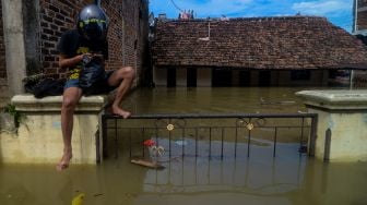 Seorang warga menaiki pagar rumahnya saat banjir melanda Kampung Bojongasih, Dayeuhkolot, Kabupaten Bandung, Jawa Barat, Selasa (25/5/2021). ANTARA FOTO/Raisan Al Farisi