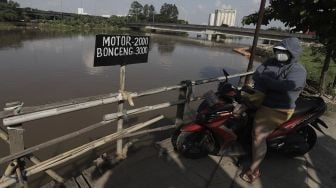 PSejumlah pengendara sepeda motor menunggu perahu eretan untuk menyeberangi Kali Cagak, Jakarta Utara, Selasa (25/5/2021). [Suara.com/Angga Budhiyanto]