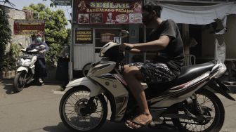 Warga menggunakan sepeda motor keluar dari Gang Usman Tepos, RT 004 RW 002 Kelurahan Srengseng Sawah, Jagakarsa, Jakarta Selatan, Jumat (28/5/2021). [Suara.com/Angga Budhiyanto]