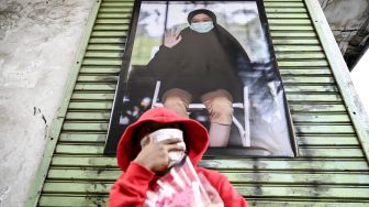 Seorang bocah duduk di depan karya foto saat pameran fotografi bertajuk Meredah COVID-19 di kawasan Pasar Lama, Tangerang, Banten, Minggu (30/5/2021). 
