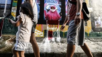 Warga melintas di depan karya foto saat pameran fotografi bertajuk Meredah COVID-19 di kawasan Pasar Lama, Tangerang, Banten, Minggu (30/5/2021).  ANTARA FOTO/Muhammad Adimaja
