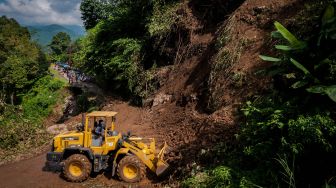 Pekerja menggunakan alat berat untuk membersihkan material longsor di Kecamatan Lebakgedong, Lebak, Banten, Minggu (30/5/2021). ANTARA FOTO/Muhammad Bagus Khoirunas
