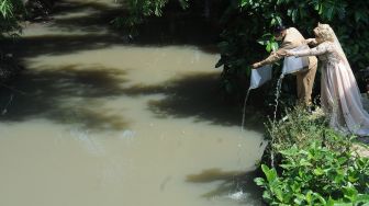 Sepasang pengantin menebar benih ikan lele di aliran sungai wilayah Juwiring, Klaten, Jawa Tengah, Minggu (30/5/2021). . ANTARA FOTO/Aloysius Jarot Nugroho