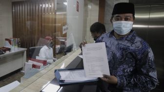 Koordinator Masyarakat Anti Korupsi Indonesia (MAKI) Boyamin Saiman (kanan) menunjukkan berkas uji materi di Mahkamah Konstitusi, Jakarta, Senin (31/5/2021). [Suara.com/Angga Budhiyanto]