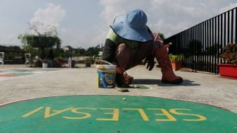 Petugas menyelesaikan pembuatan permainan tradisional di Taman Sungai Kendal, Cilincing, Jakarta Utara, Senin (31/5/2021). [Suara.com/Dian Latifah]