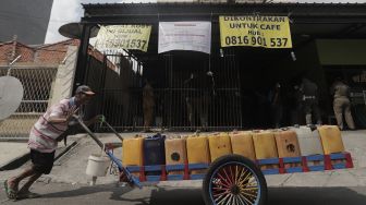 Penjual air keliling berjalan di depan Hotel Wisma Prima yang ditutup di Mangga Besar, Taman Sari, Jakarta Barat, Senin (31/5/2021). [Suara.com/Angga Budhiyanto]