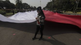 Sejumlah massa mengibarkan bendera merah putih raksasa di kawasan Patung Kuda Arjuna Wiwaha, Jakarta, Rabu (2/6/2021). [Suara.com/Angga Budhiyanto]