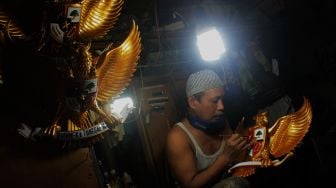 Perajin menyelesaikan pembuatan Patung Garuda di Jalan Bali Raya, Kalimalang, Jakarta Timur, Rabu (2/6/2021). [Suara.com/Dian Latifah]