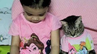 Bikin Gemas, Momen Bocah dan Kucing Ini Kompak Pakai Baju Sama