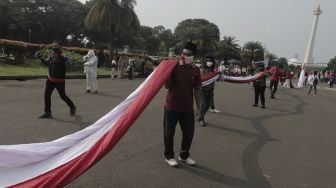 Sejumlah massa bersiap mengibarkan bendera merah putih raksasa di kawasan Patung Kuda Arjuna Wiwaha, Jakarta, Rabu (2/6/2021). [Suara.com/Angga Budhiyanto]