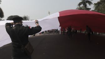 Sejumlah massa mengibarkan bendera merah putih raksasa di kawasan Patung Kuda Arjuna Wiwaha, Jakarta, Rabu (2/6/2021). [Suara.com/Angga Budhiyanto]