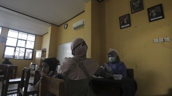 Petugas kesehatan memeriksa kondisi kesehatan warga sebelum mendapatkan vaksin COVID-19 di MTs As-Syafiiyah, Cilangkap, Jakarta, Kamis (3/6/2021). [Suara.com/Angga Budhiyanto]