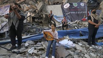 Musisi Palestina tampil di antara puing-puing reruntuhan Menara Hanadi di Kota Gaza, pada (2/6/2021). [MOHAMMED ABED / AFP]