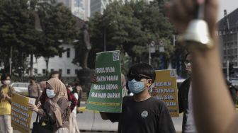 Sejumlah aktivis lingkungan hidup membawa poster saat melakukan aksi Jeda Untuk Iklim di kawasan Patung Kuda Arjuna Wiwaha, Jakarta, Jumat (4/6/2021). [Suara.com/Angga Budhiyanto]