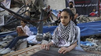 Musisi Palestina tampil di antara puing-puing reruntuhan Menara Hanadi di Kota Gaza, pada (2/6/2021). [MOHAMMED ABED / AFP]