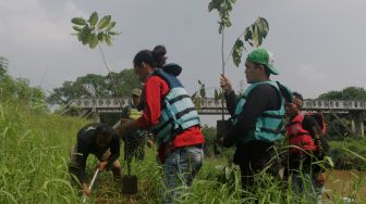 Sejumlah relawan menanam bibit pohon di bantaran kali Cikarang, Kabupaten Bekasi, Minggu (6/6/2021).  [Suara.com/Dian Latifah]