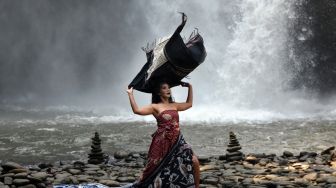 Model menampilkan rancangan kain tradisional atau wastra nusantara yang diperagakan di area air terjun Tegenungan, Gianyar, Bali, Sabtu (5/6/2021). ANTARA FOTO/Nyoman Hendra Wibowo