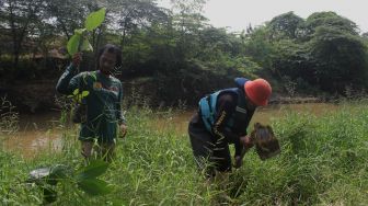 Sejumlah relawan menanam bibit pohon di bantaran kali Cikarang, Kabupaten Bekasi, Minggu (6/6/2021).  [Suara.com/Dian Latifah]