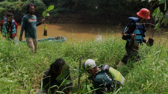 Sejumlah relawan menanam bibit pohon di bantaran kali Cikarang, Kabupaten Bekasi, Minggu (6/6/2021).  [Suara.com/Dian Latifah]