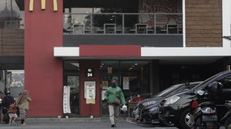 Seorang pengemudi ojek daring membawa pesanan pelanggan di gerai restoran cepat saji McDonald's Raden Saleh, Jakarta, Kamis (10/6/2021). [Suara.com/Angga Budhiyanto]