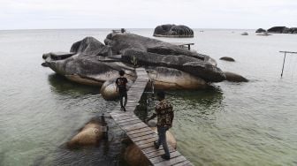 Wisatawan melintasi jembatan yang menghubungkan bebatuan granit di perairan kawasan situs geologi Alif Stone Park di Bunguran Timur, Kabupaten Natuna, Kepulauan Riau, Jumat (11/6/2021). [ANTARA FOTO/Akbar Nugroho Gumay]