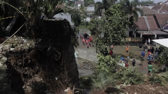 Warga memantau arus air yang masuk dan menyebabkan banjir akibat jebolnya tanggul usai tertimpa tanah longsor di Perumahan Nerada Estate Ciputat, Tangerang Selatan, Banten, Sabtu (12/6/2021). [Suara.com/Angga Budhiyanto]